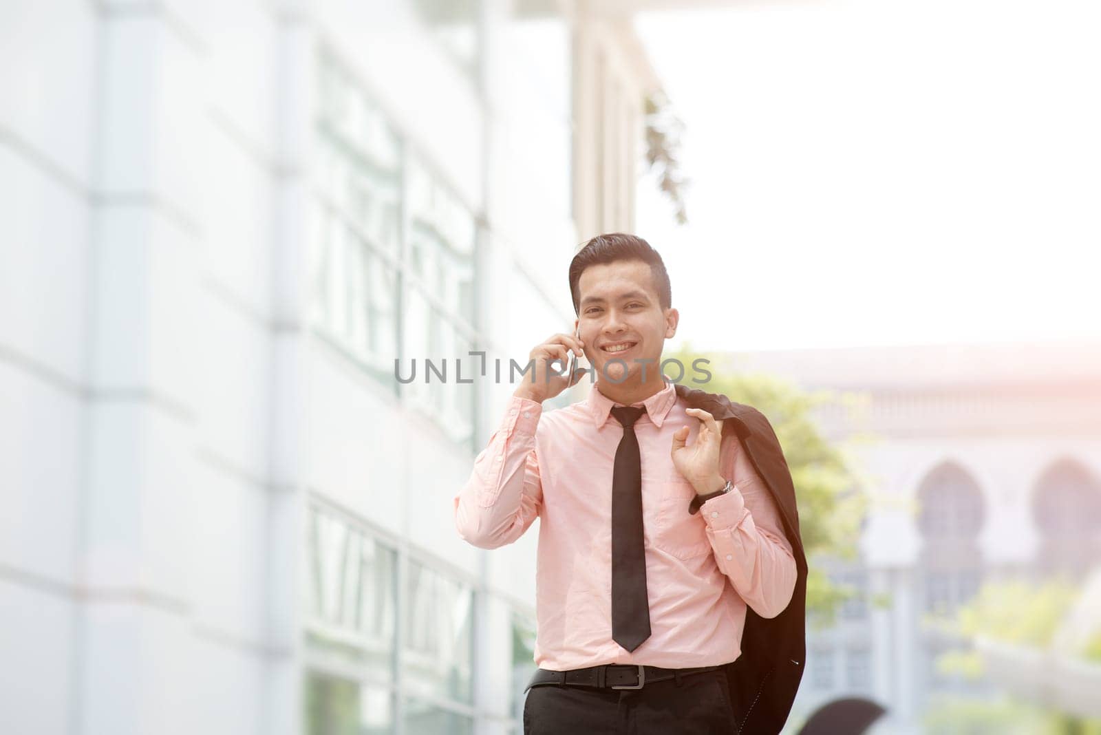 Young entrepreneur talking on the phone, walking on city street.