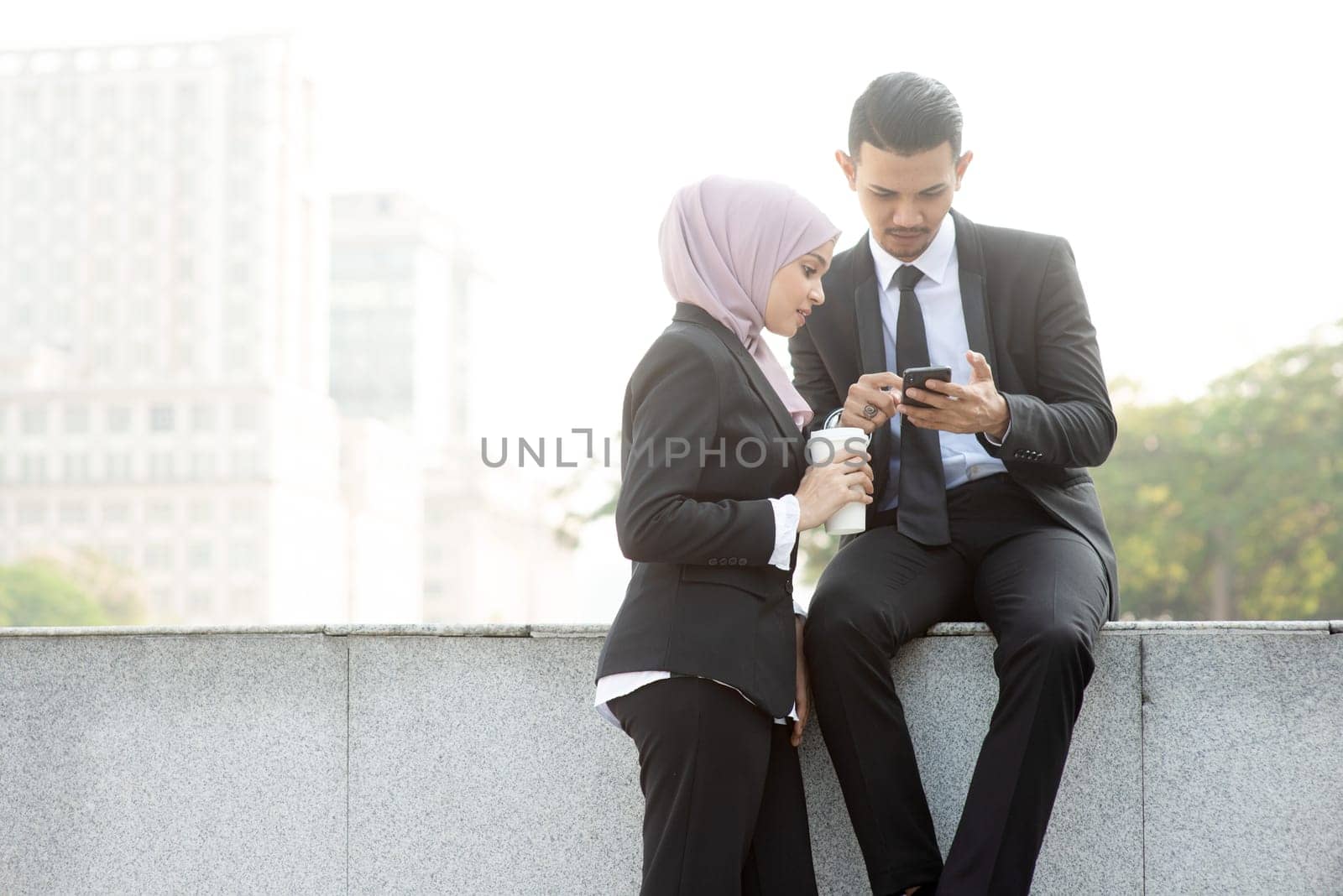 Business people using smartphone outside office.