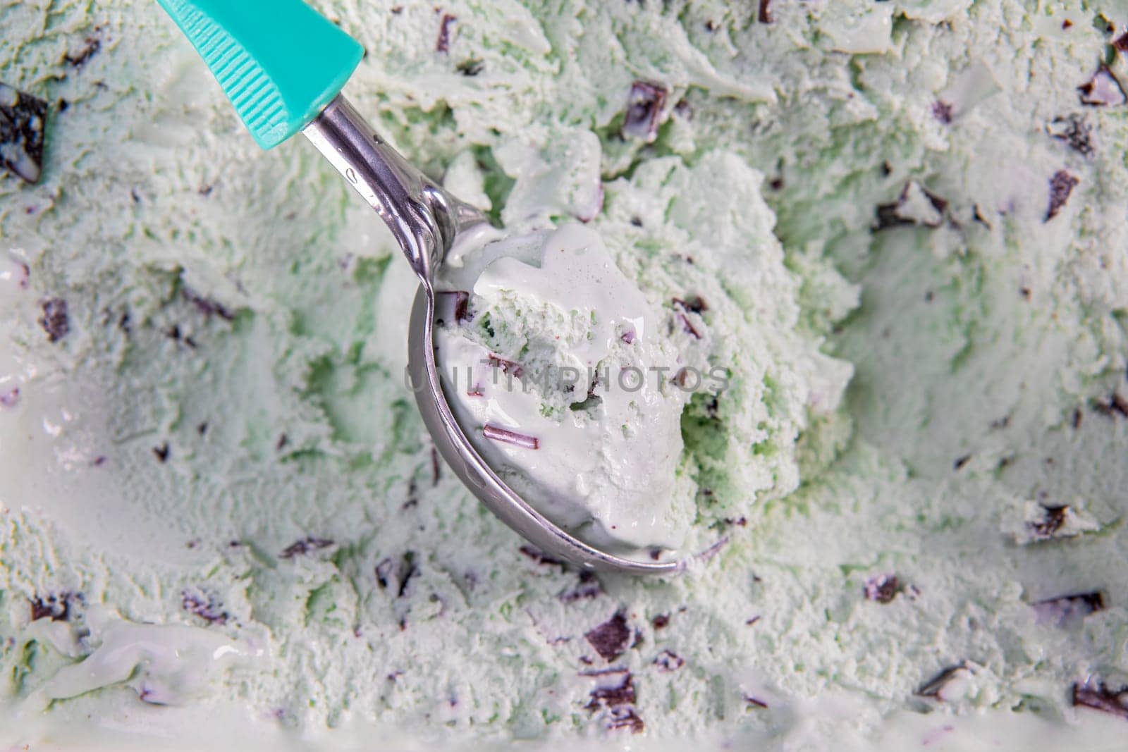 Top view of mint flavour ice cream with chocolate flakes in box. Focus on ice cream in scoop.