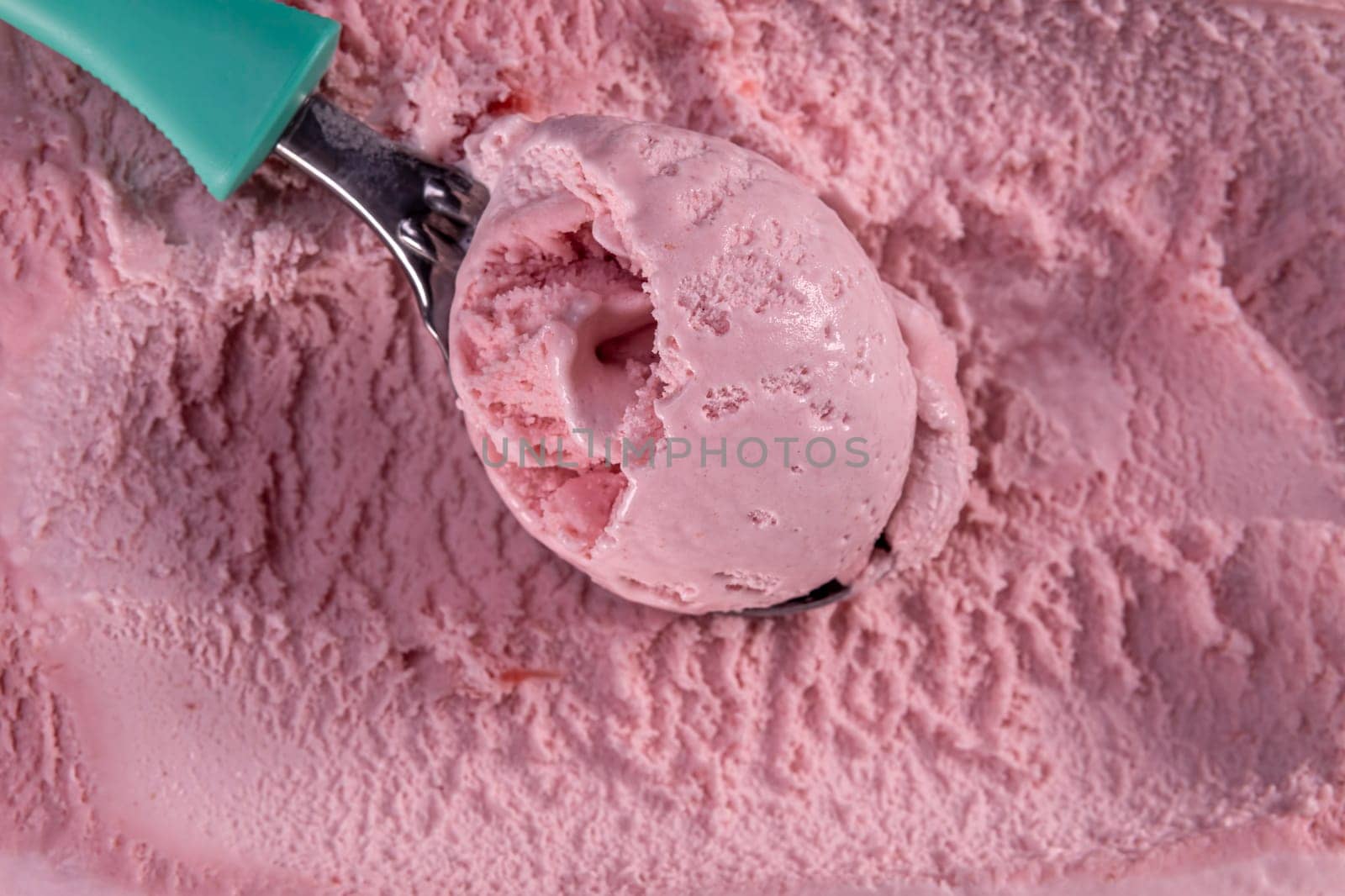 Top view of strawberry flavour ice cream with scoop in box. Focus on scoop.