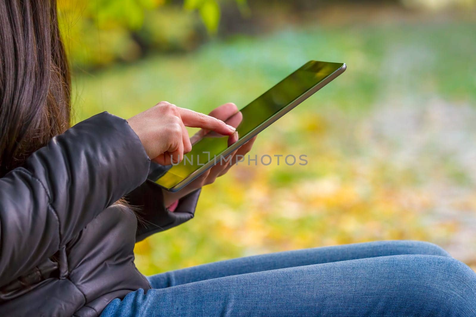 Teenage girl using digital tablet computer in autumn park closeup