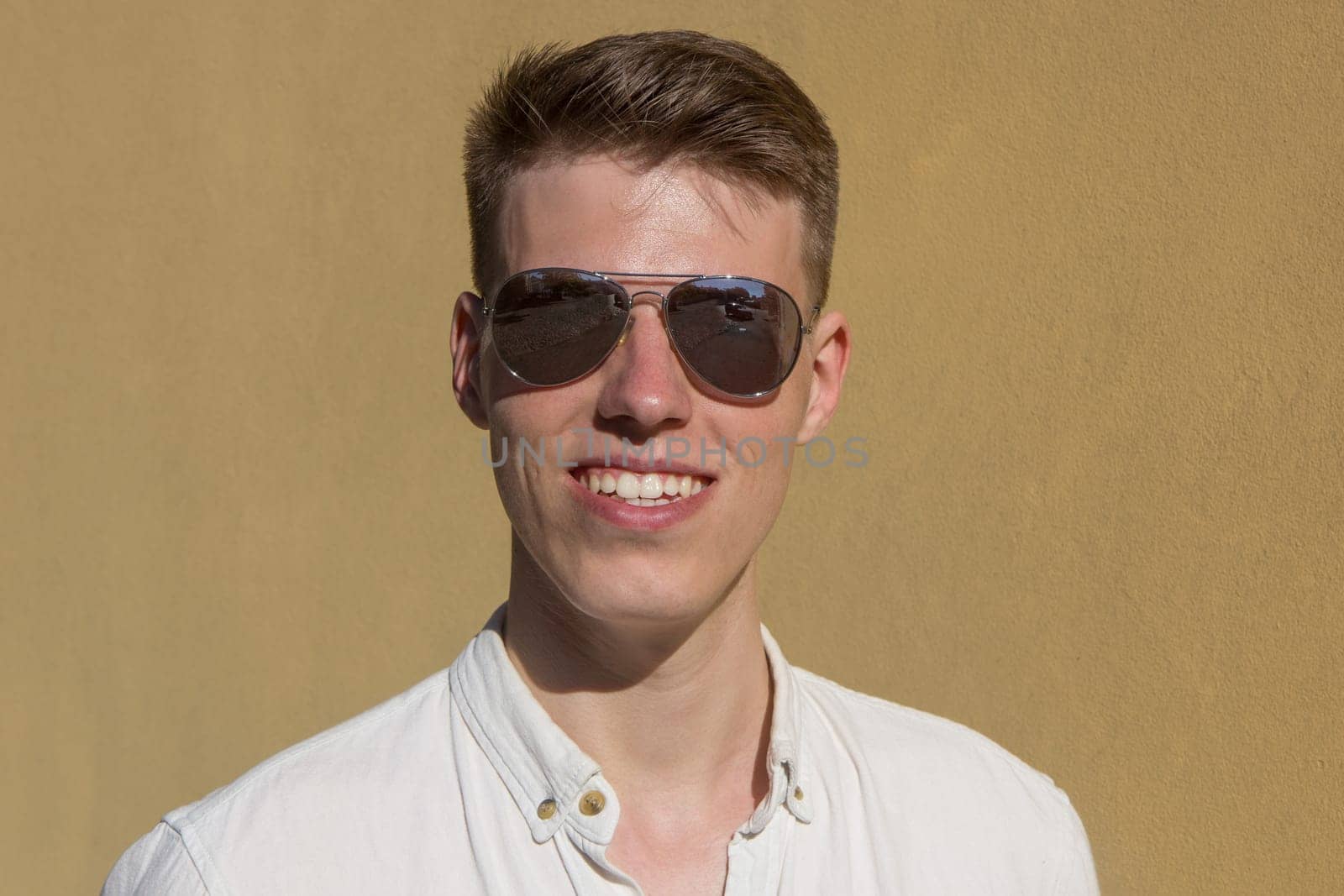 portrait of a handsome man dressed in white shirt against yellow wall