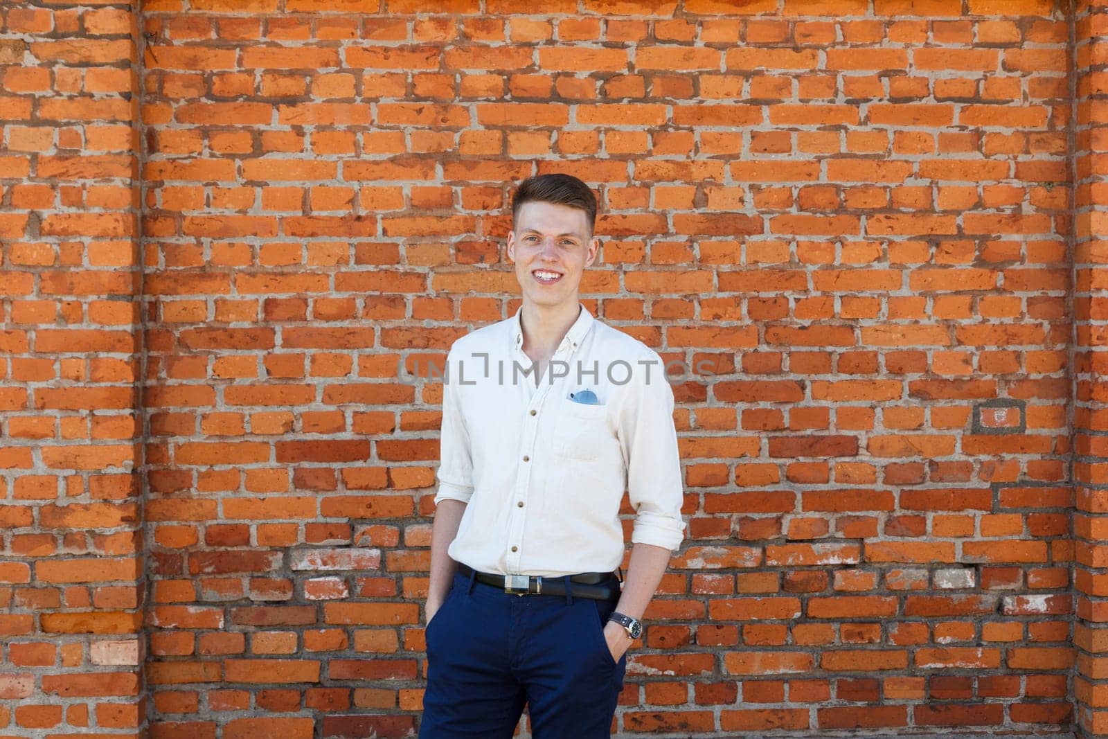 Portrait of a casually dressed young businessman standing against a brick wall