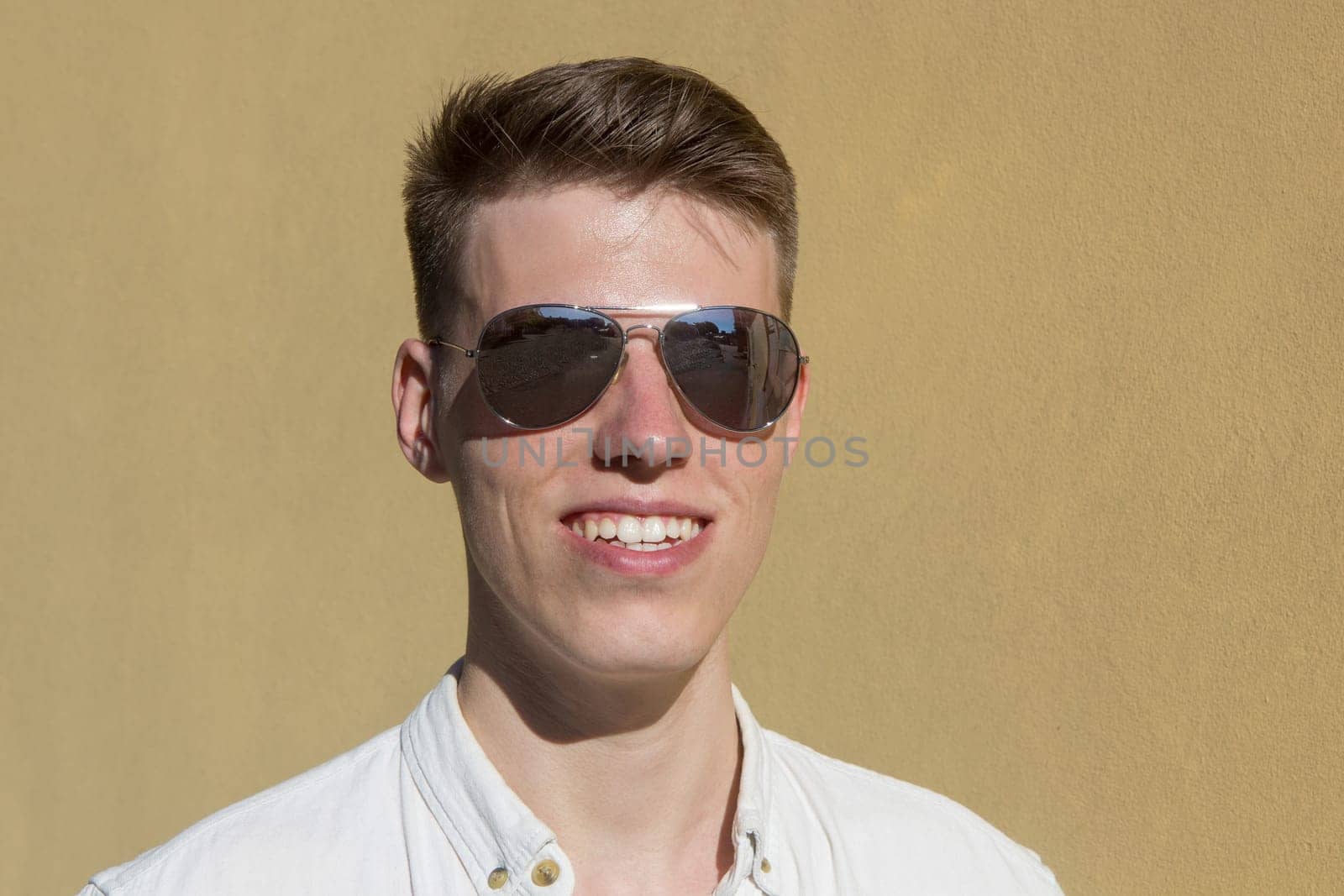 portrait of a handsome man dressed in white shirt against yellow wall