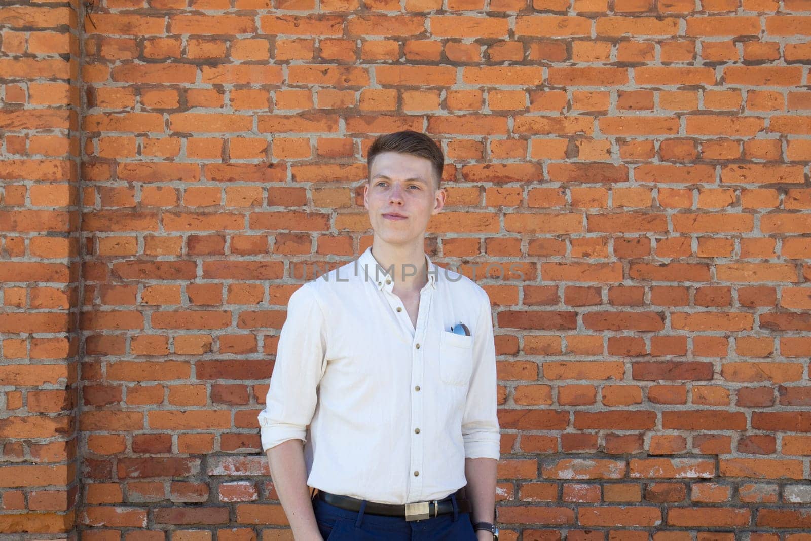 Portrait of a casually dressed young businessman standing against a brick wall
