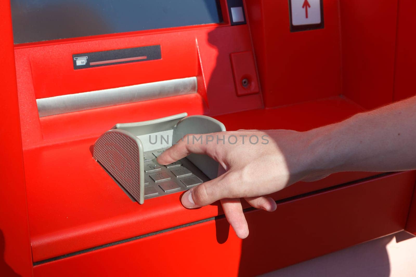 close up of hand entering pin code at cash machine