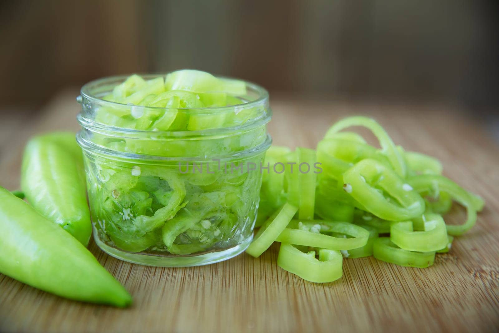 Fresh sliced banana peppers on a cutting board with jar ready for pickling.