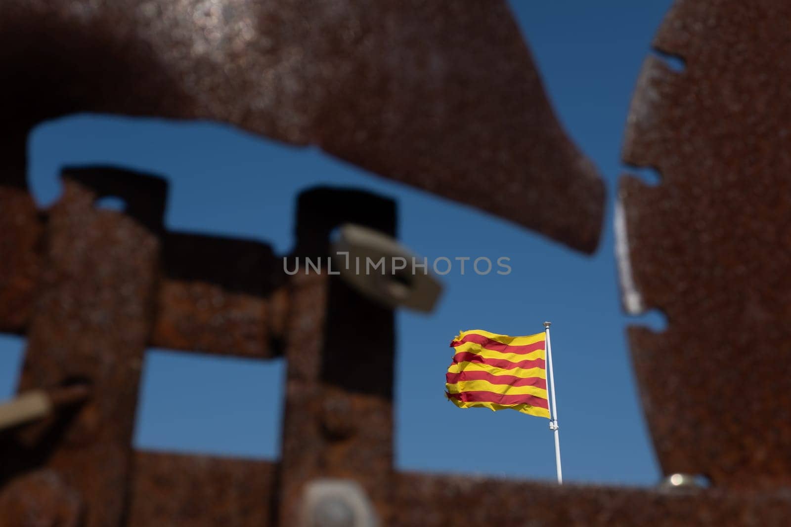 Closeup of blurred weather vane with padlocks and the Catalan flag focused in the background. Concepts of closure and frustration.