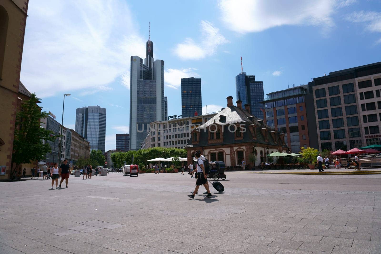 Frankfurt, Germany - July 06, 2019: Pedestrians and visitors strolling through town on the square in front of the Hauptwache with skyscrapers of the financial district in the background on July 06, 2019 in Frankfurt...