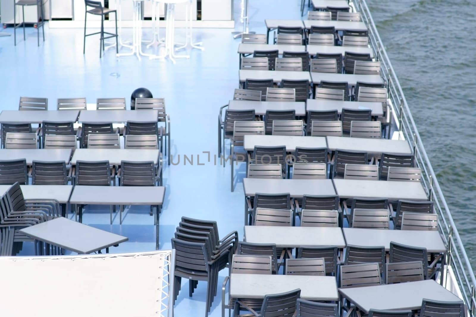 The top view of a noble and well maintained sundeck a passenger ship with tables and chairs...