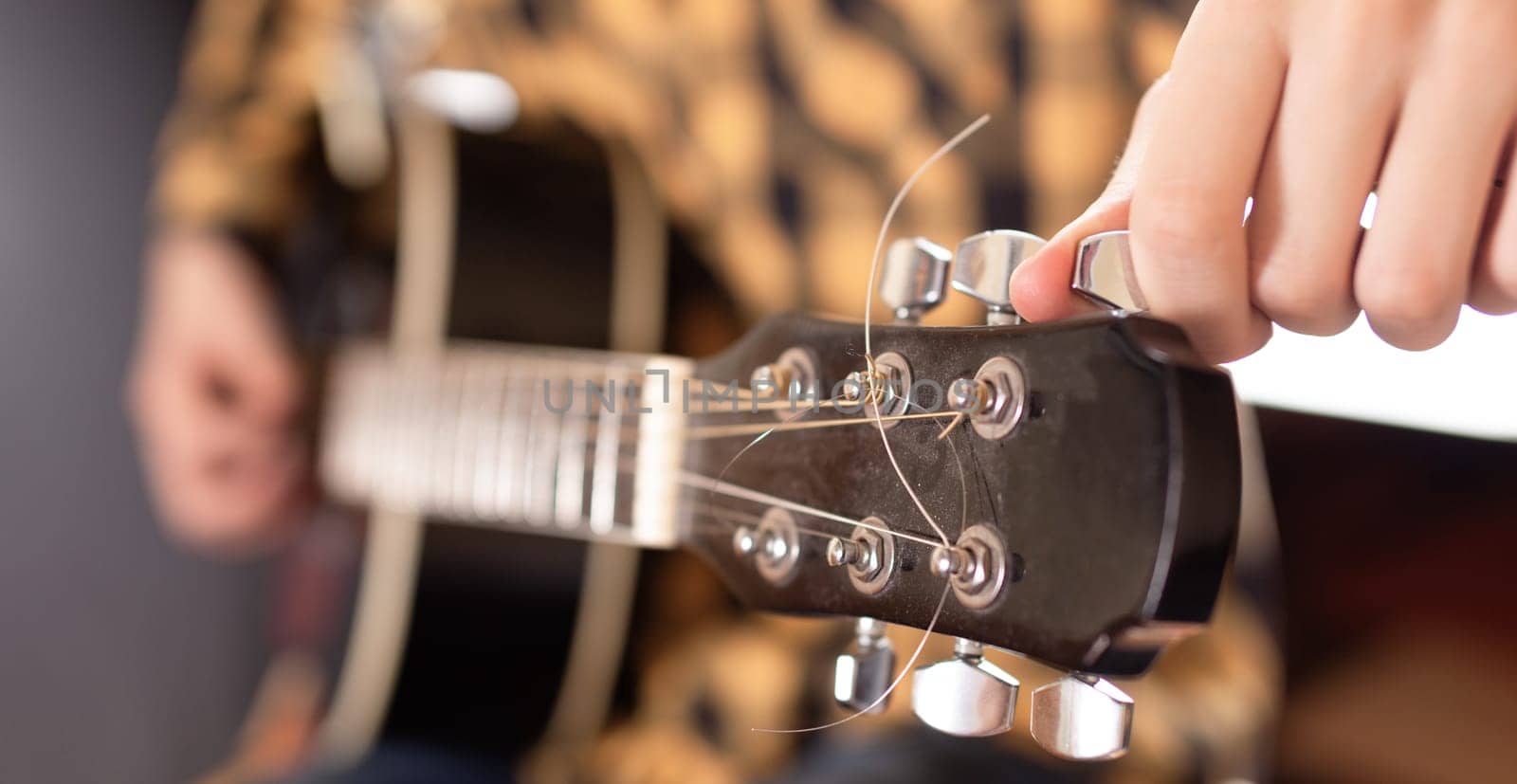 The young man tuning the electric guitar. Closeup