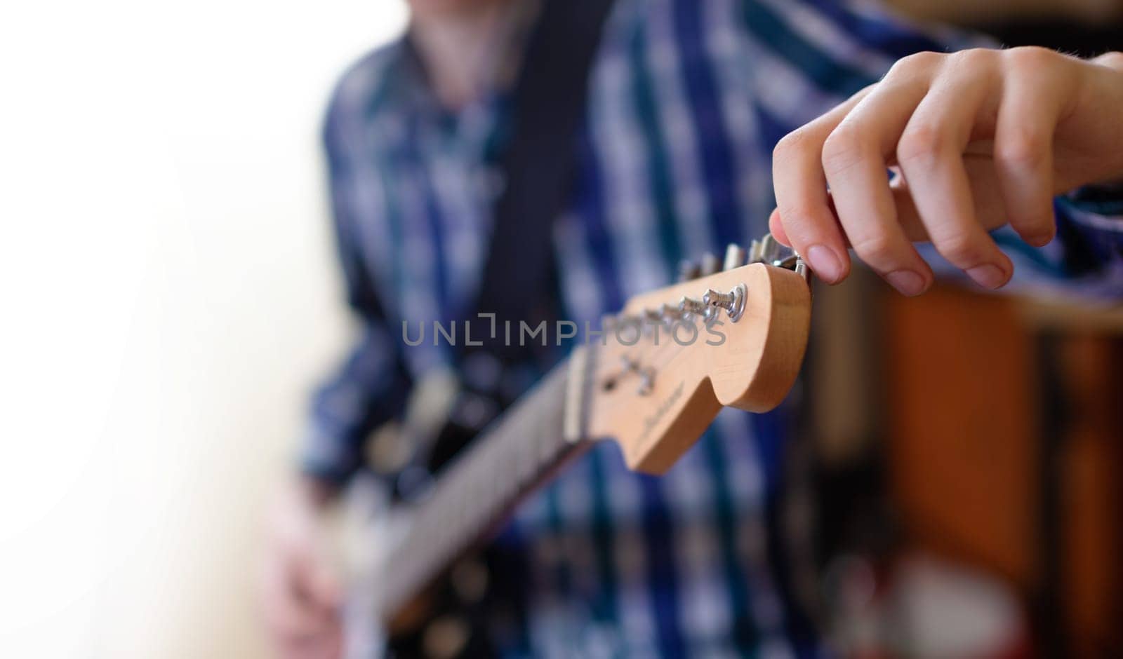The young man tuning the electric guitar. Closeup