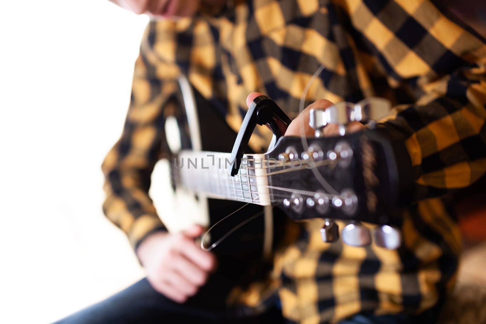 The young man tuning the electric guitar. Closeup