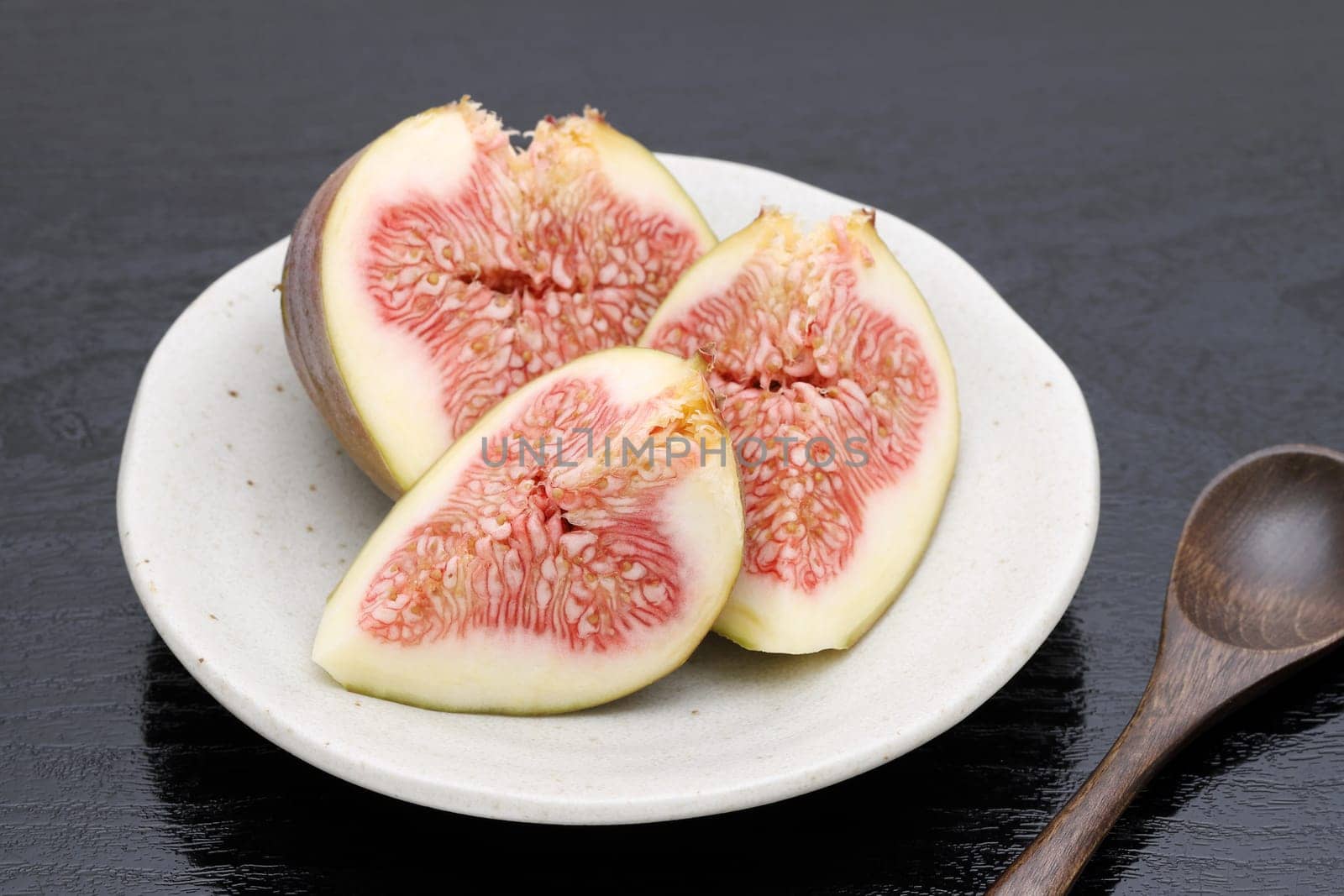 Ripe sweet fig on a plate on black background