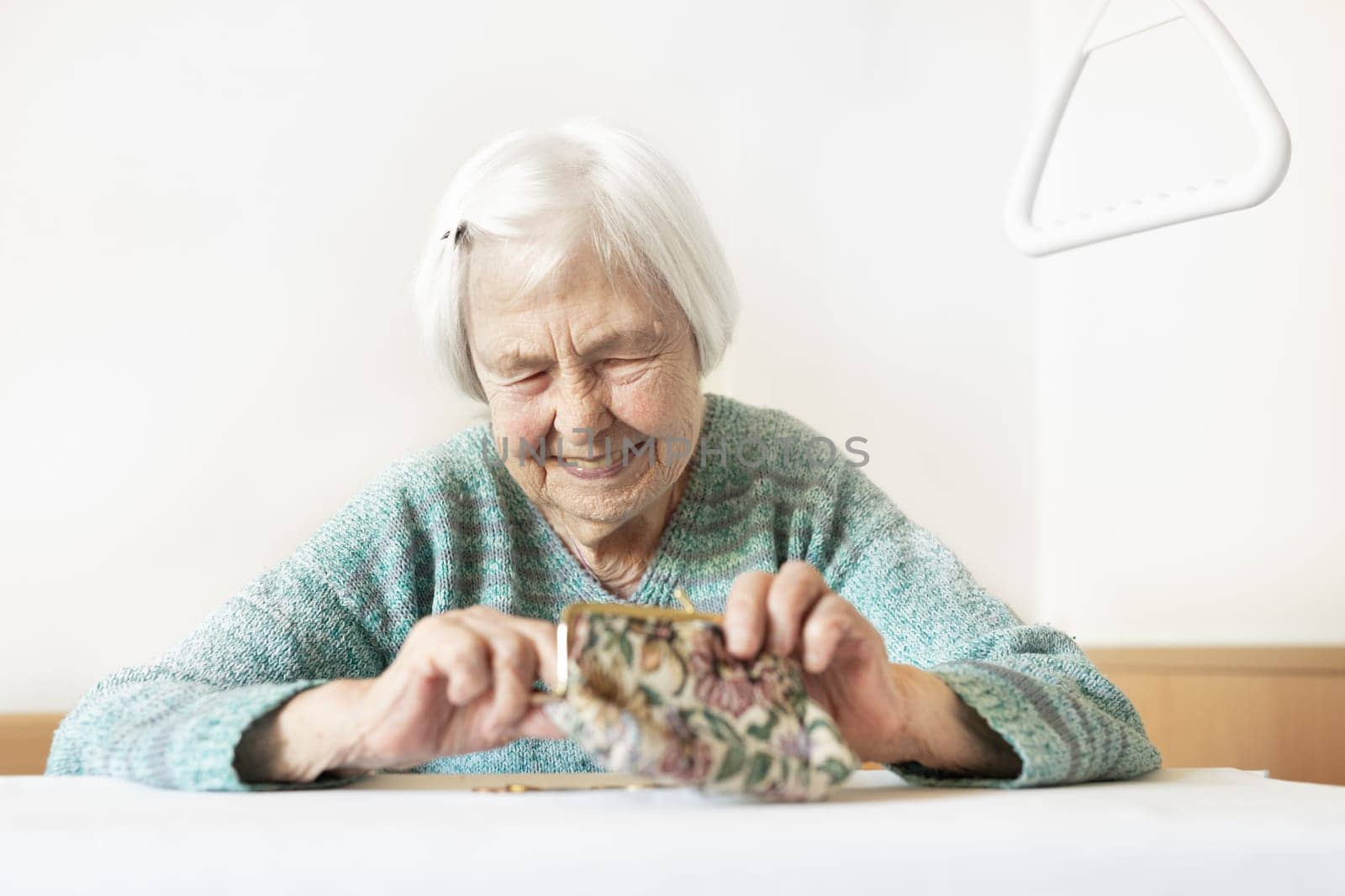 Cheerful elderly 96 years old woman sitting at table at home happy with her pension savings in her wallet after paying bills. Saving for retirement and financial planing concept.