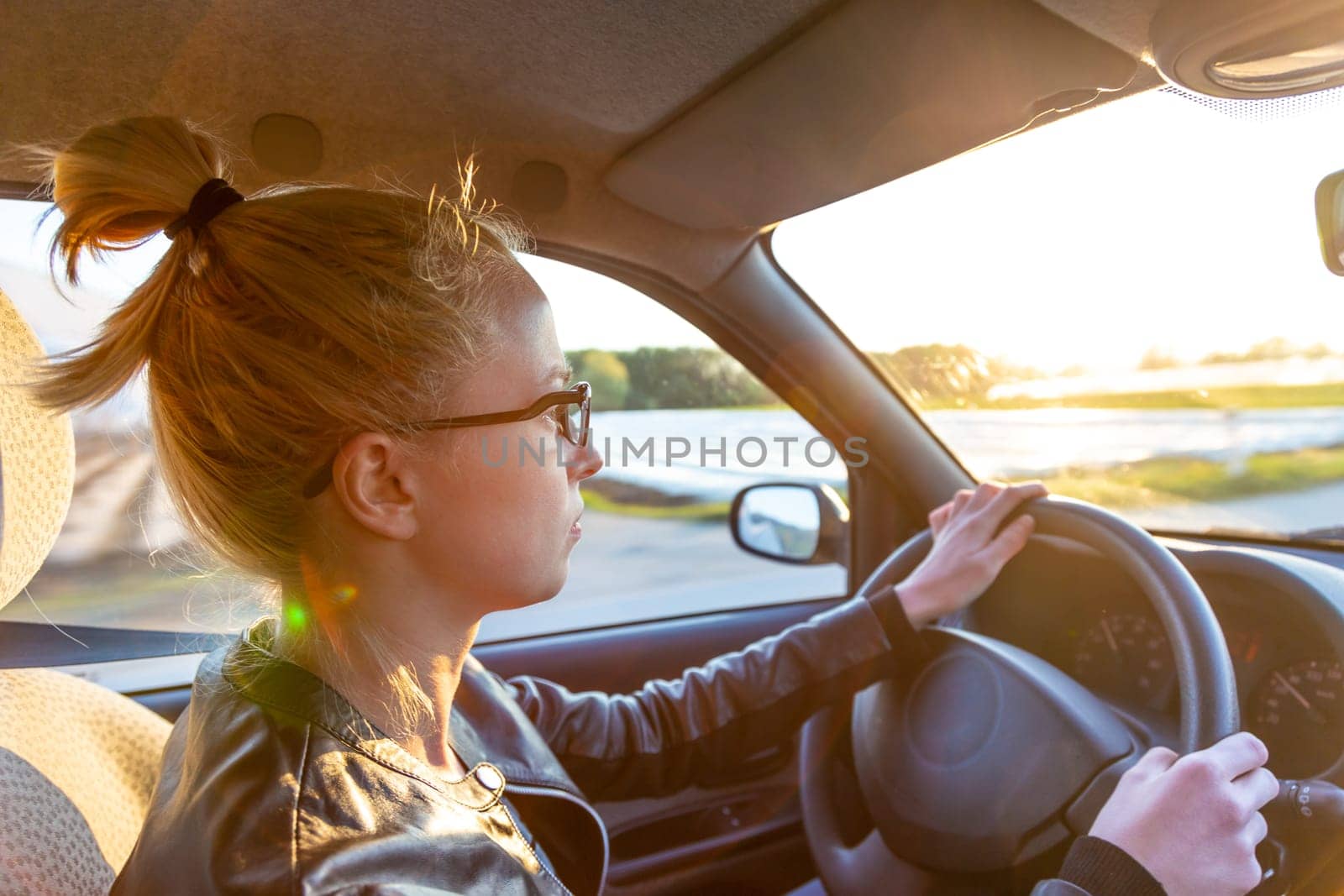 Casual caucasian woman driving a passenger car for a journey in countryside.