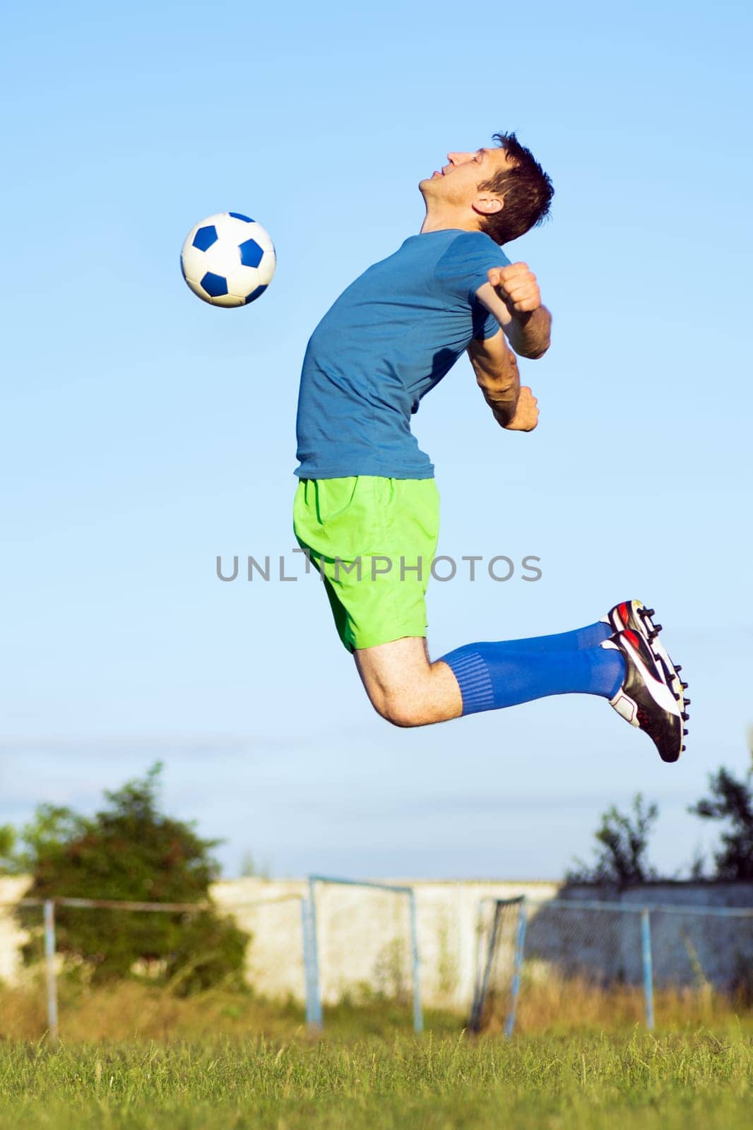 The soccer player is jumping to hitting soccer ball with chest, sport action in motion.