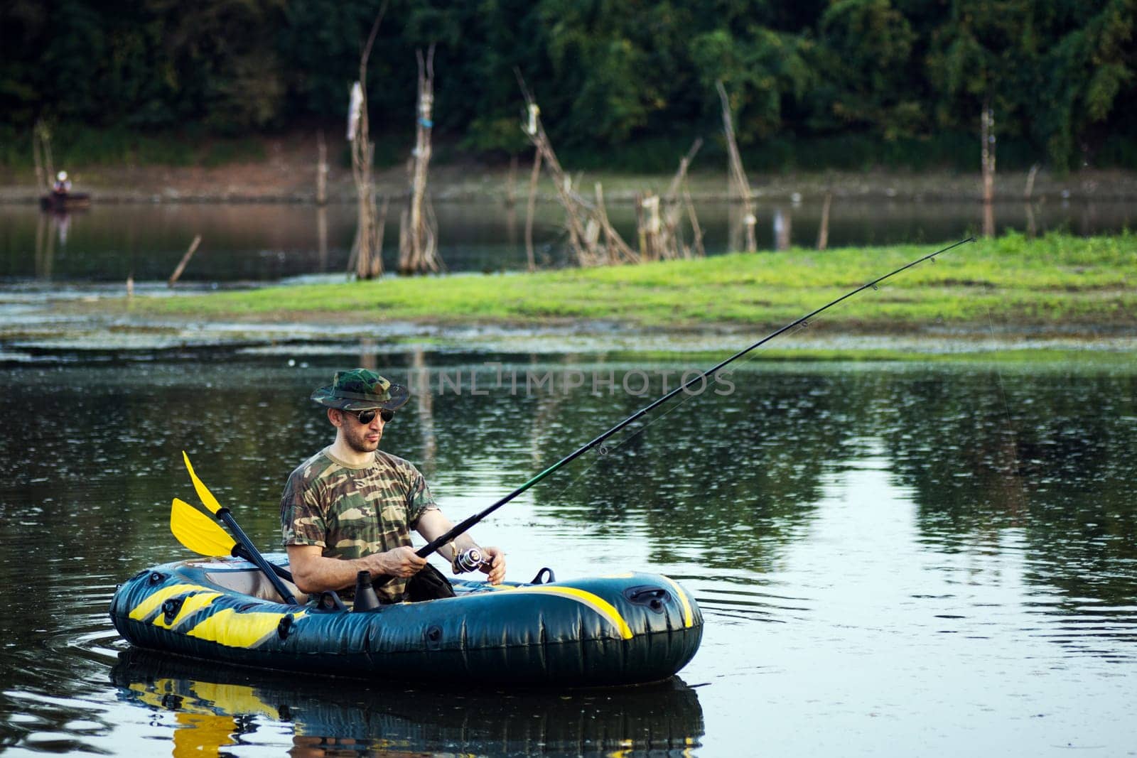 The fisherman is fishing from inflatable boat on the lake.