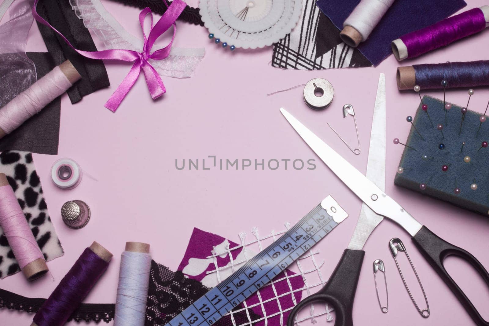 Sewing kit or sewing supplies are on pink background.