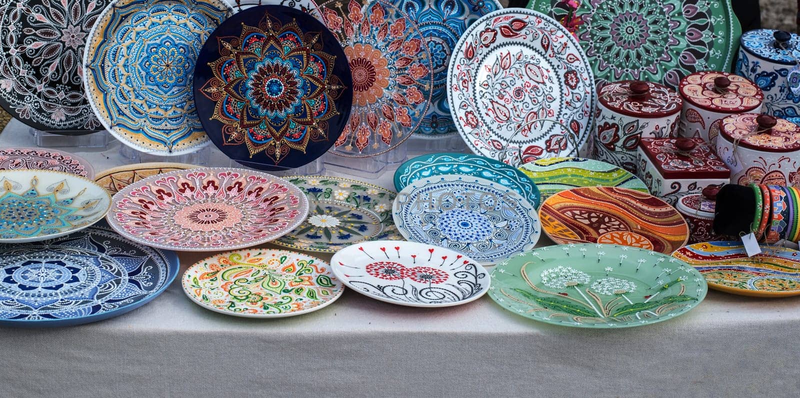Ceramic plates, hand-painted with a dot pattern, are on the counter at the festive fair