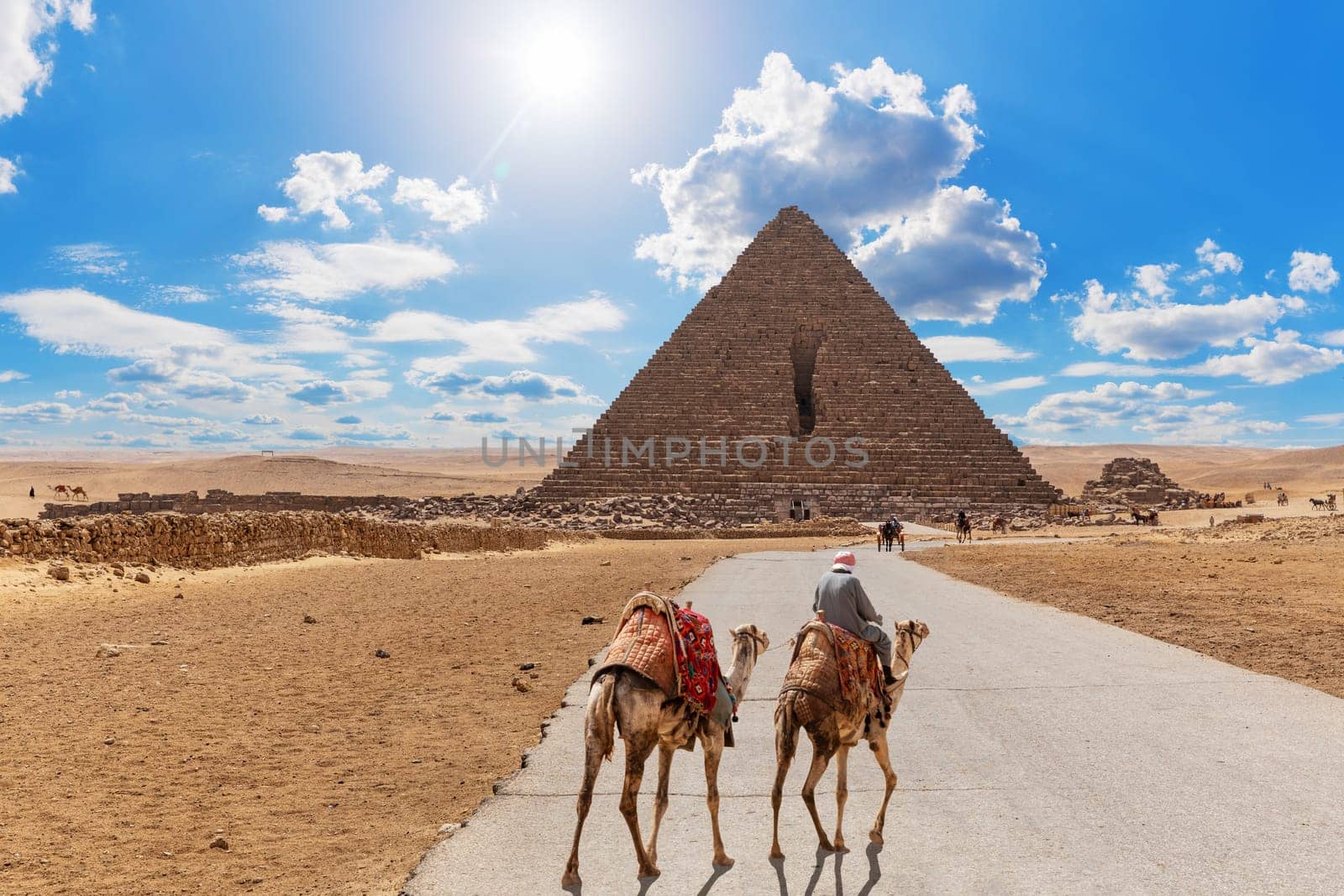 Road to the Pyramid of Menkaure and the bedouin with camels, Giza, Egypt.