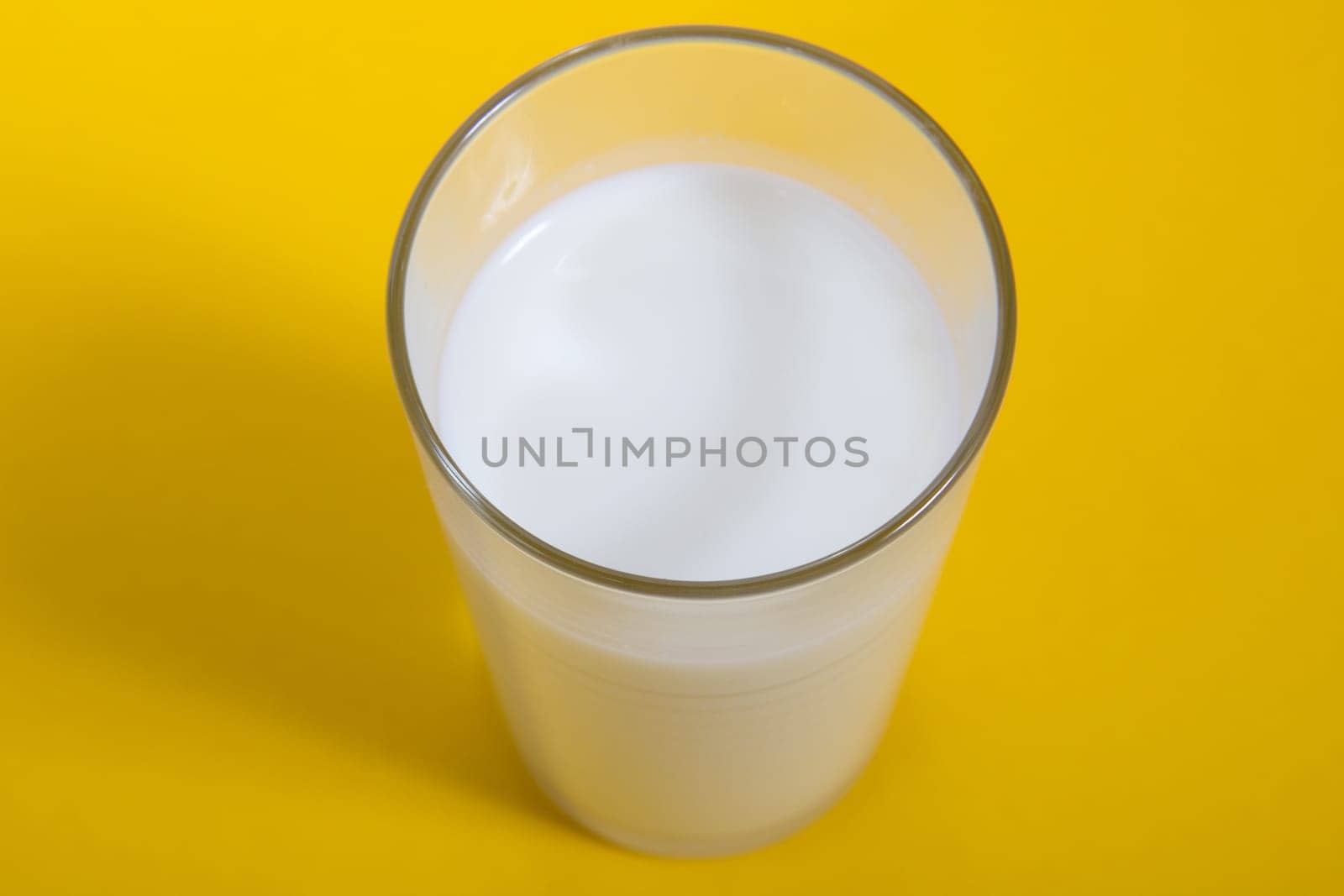 Glass of fresh milk on yellow background