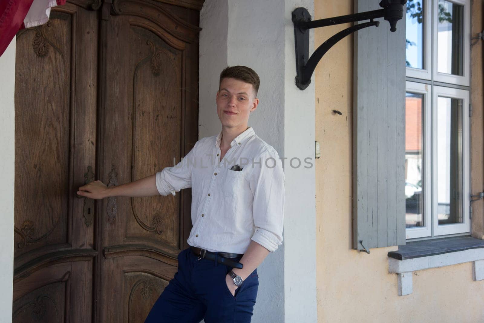 The well-dressed man stands outside by the door