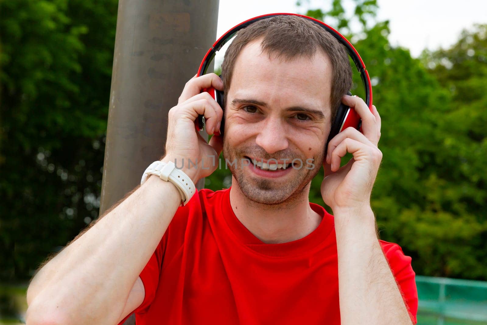 Young joyful Sportsman with red headphones in nature