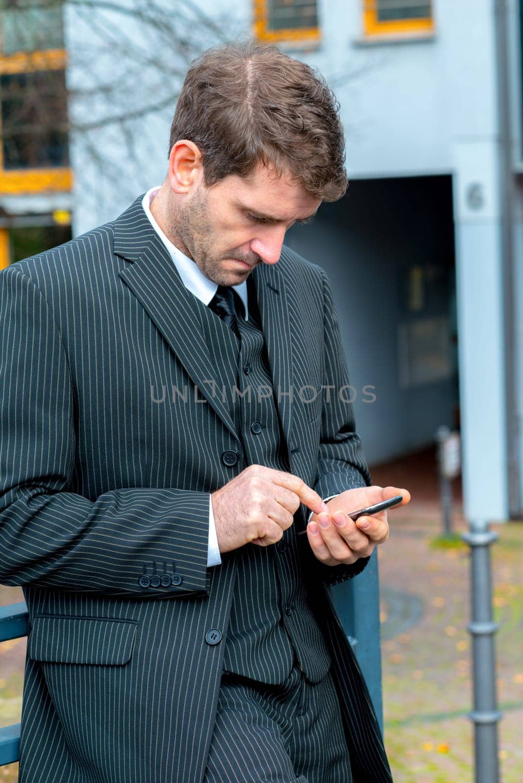 businessman in suit in front of city- background with smartphone