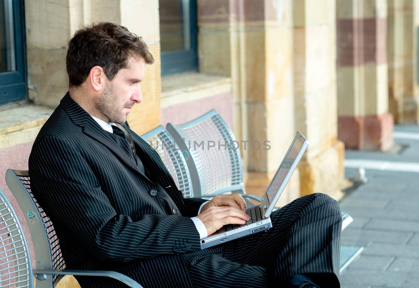 businessman in dark suit is resting and using laptop