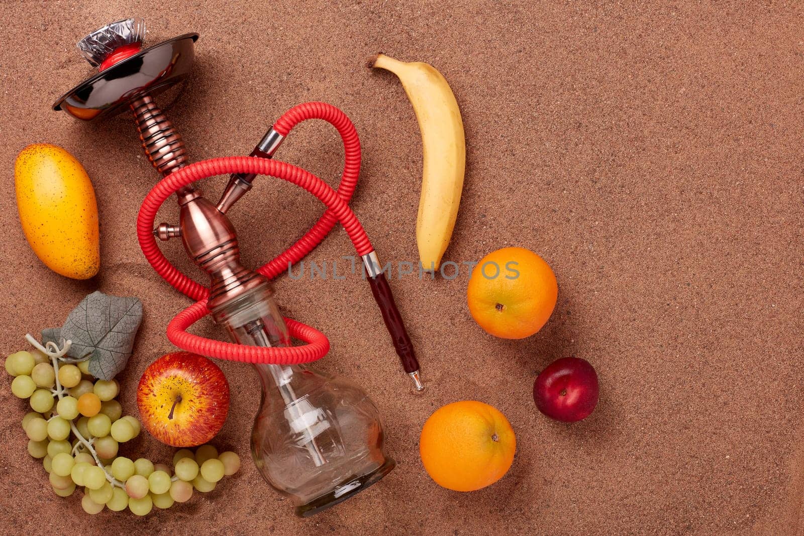 Turkish hookah (shisha) and fruit on a sand background.