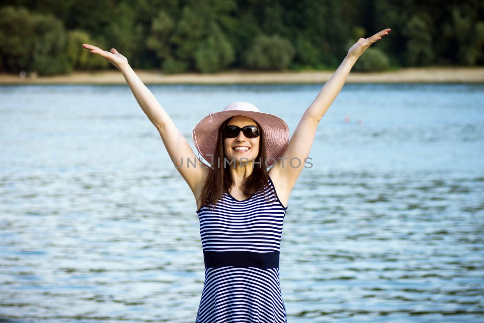 Joyful carefree woman is enjoying in freedom and summer on holiday at the riverside in nature.