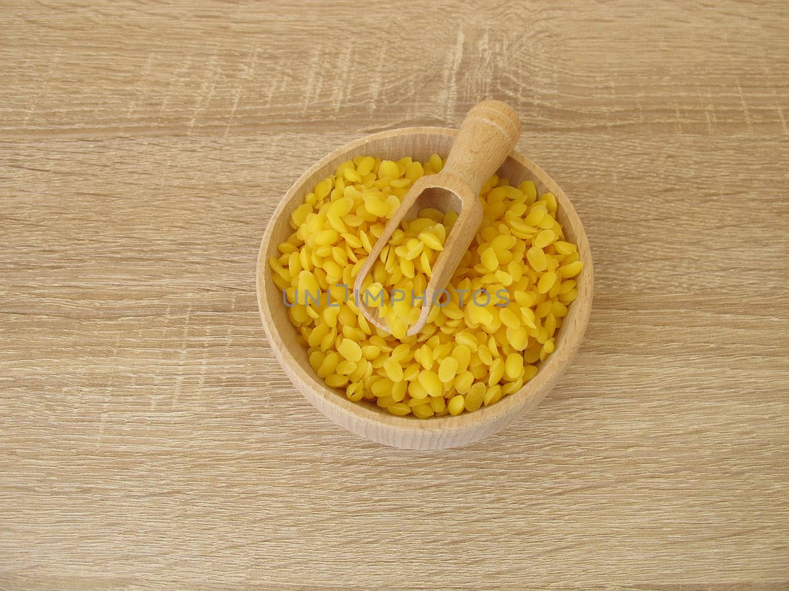Pure beeswax pastilles in a wooden bowl for natural cosmetics, candles or beeswraps