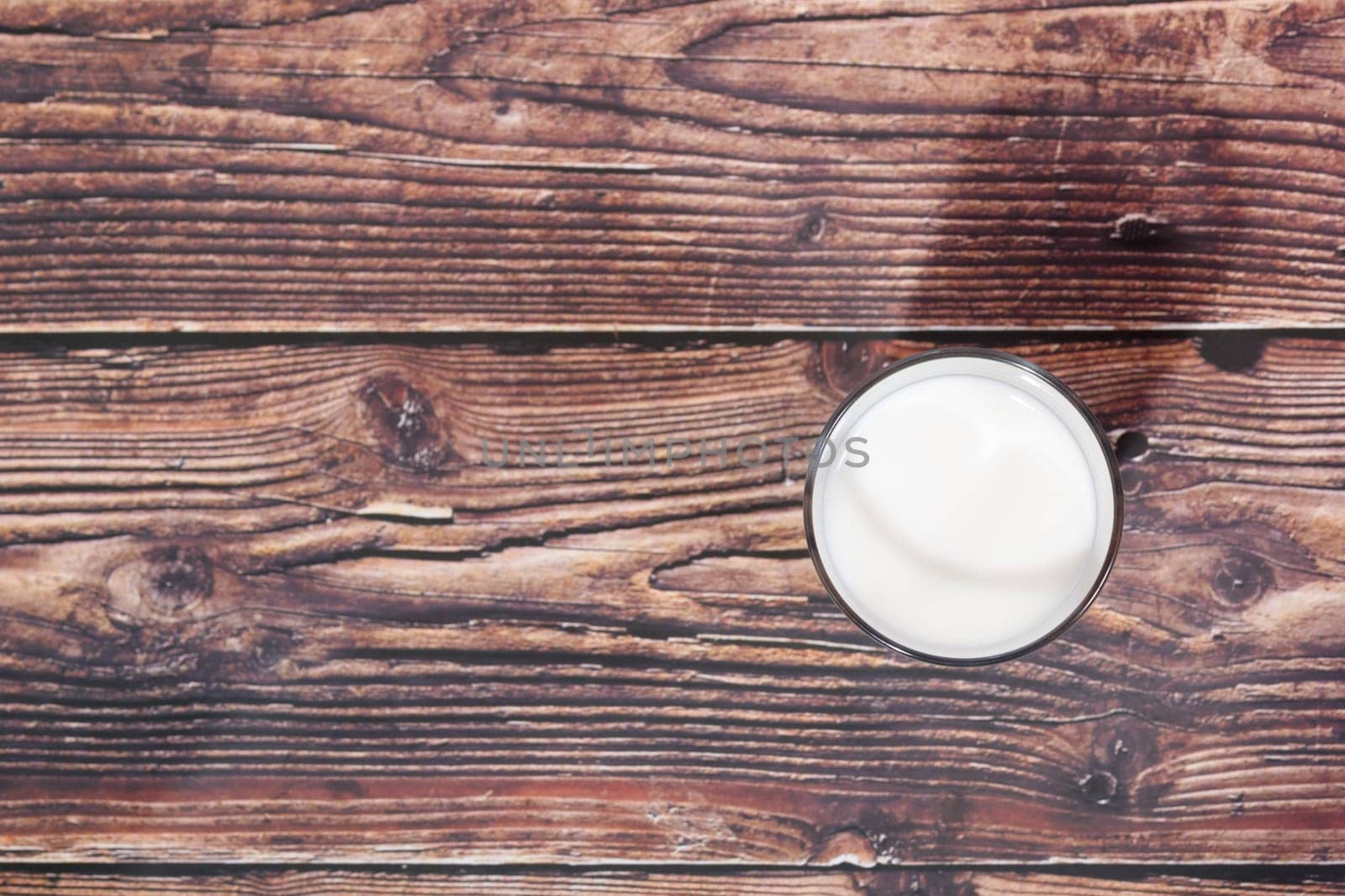 glass of milk on wooden background from above