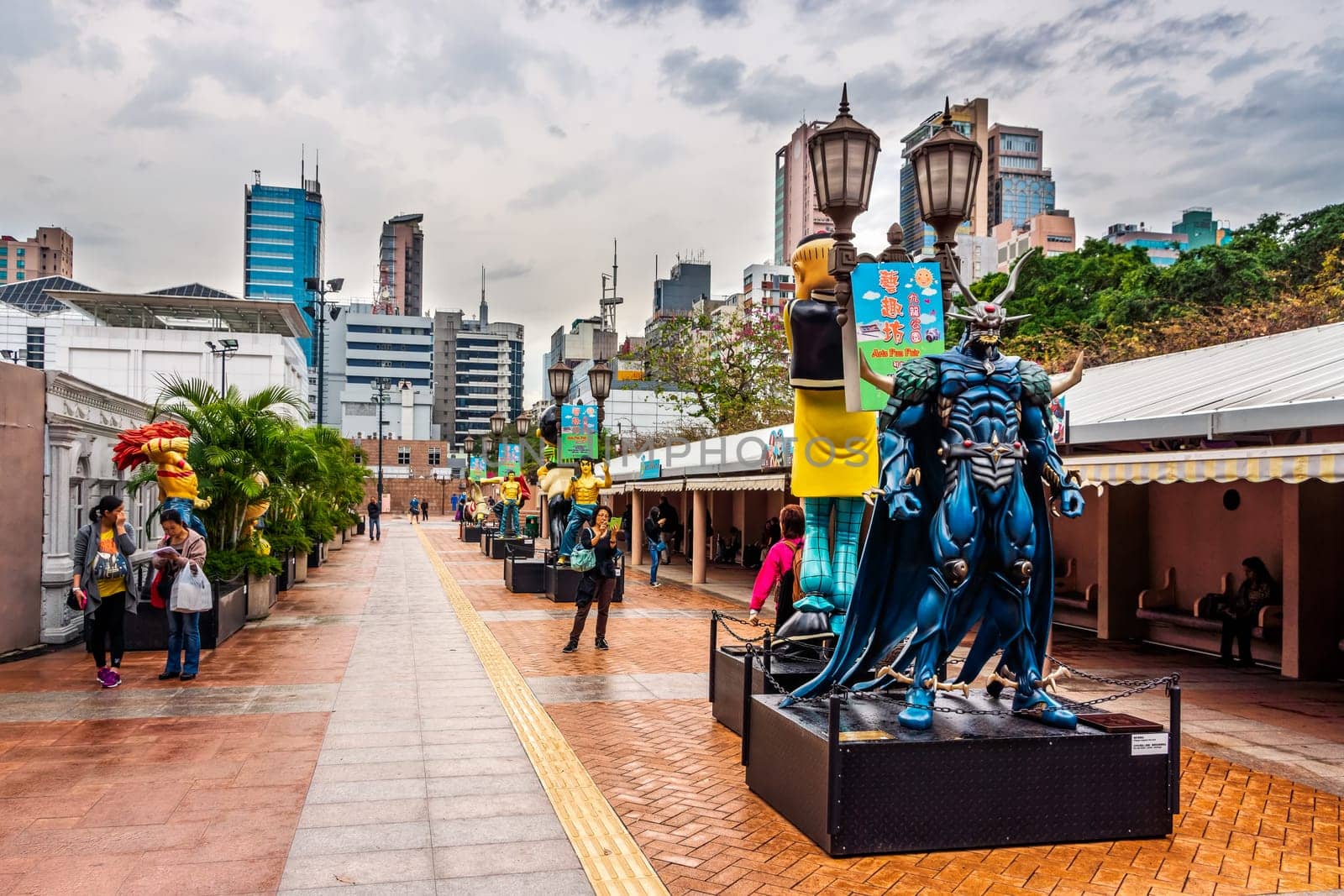 Hong Kong, China, March 2013 Statues of famous characters, in Hong Kong Avenue of Comic Stars, Kowloon Park. Urban skyline background of Tsim Sha Tsui District