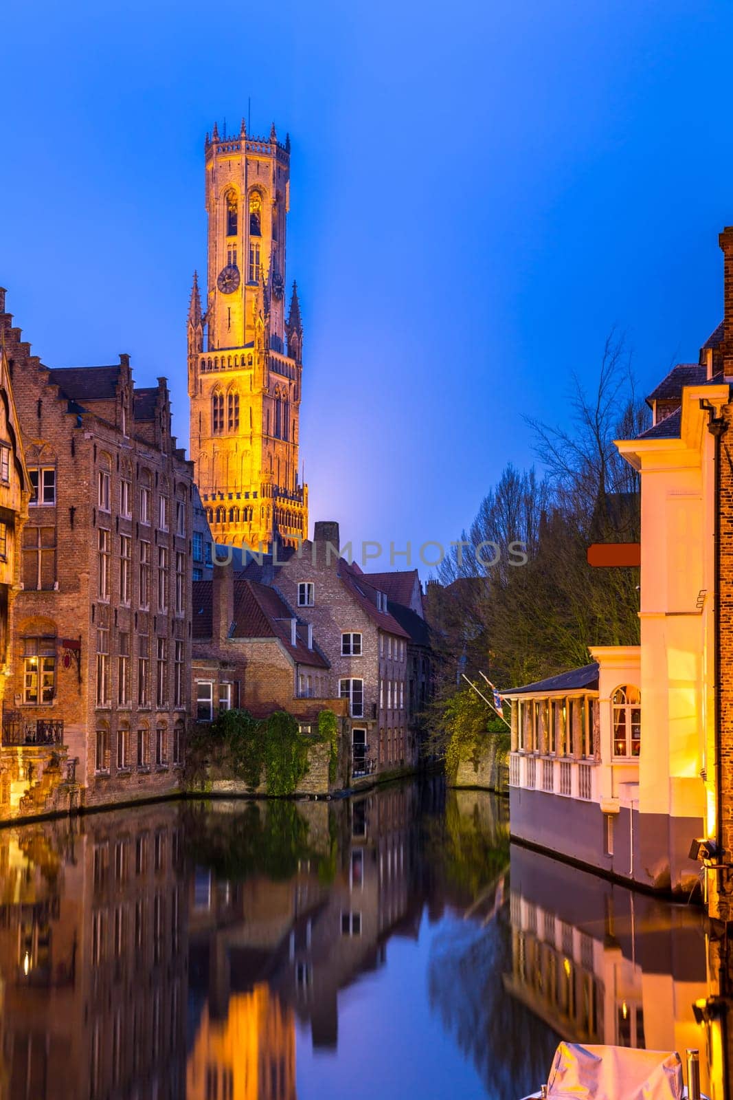Historic medieval buildings along a canal in Bruges, Belgium at dusk.
