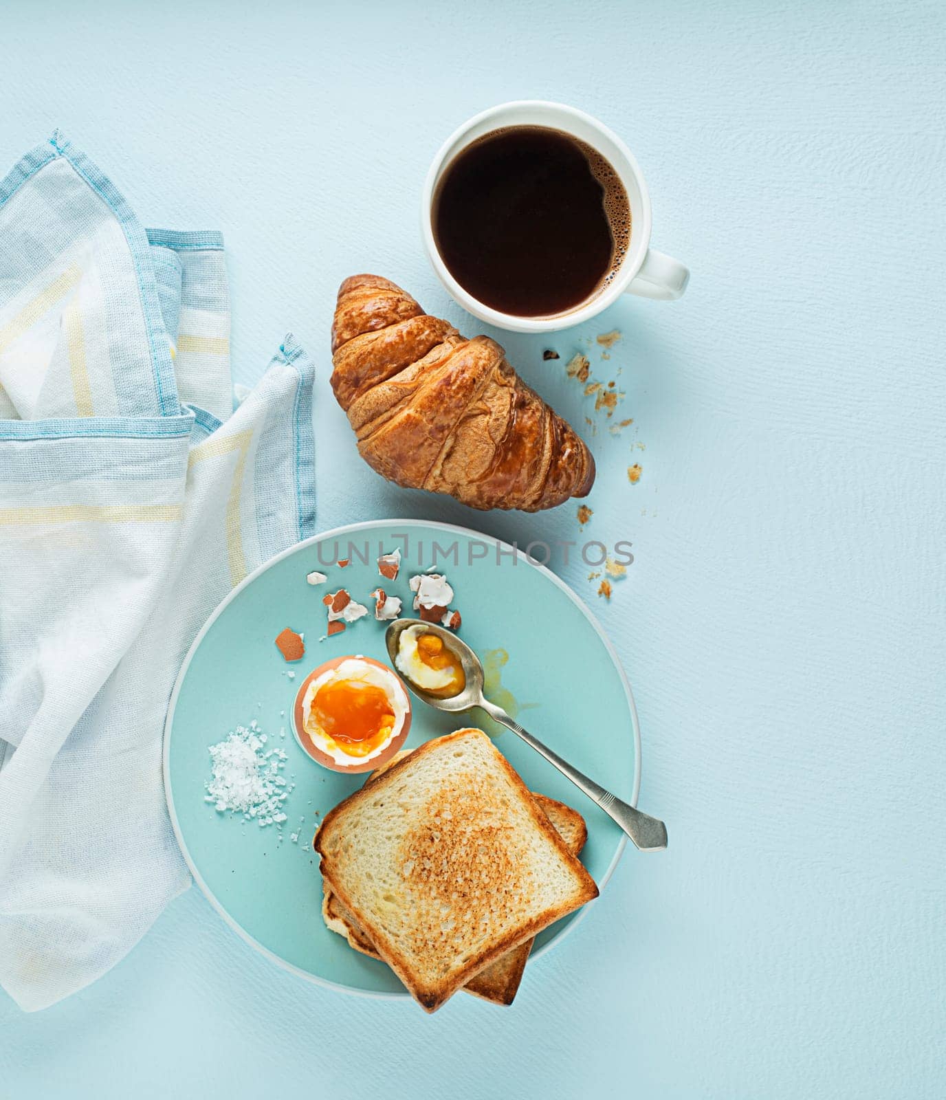 Breakfast served with croissant, coffee, boiled egg and toast. Continental breakfast table