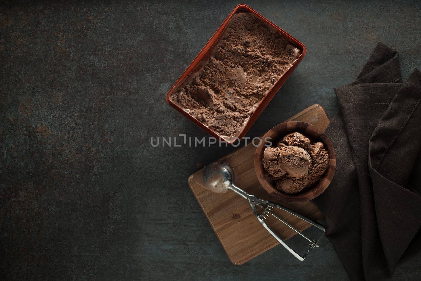 Chocolate ice cream scoop, scooped out of a container with a silver utensil
