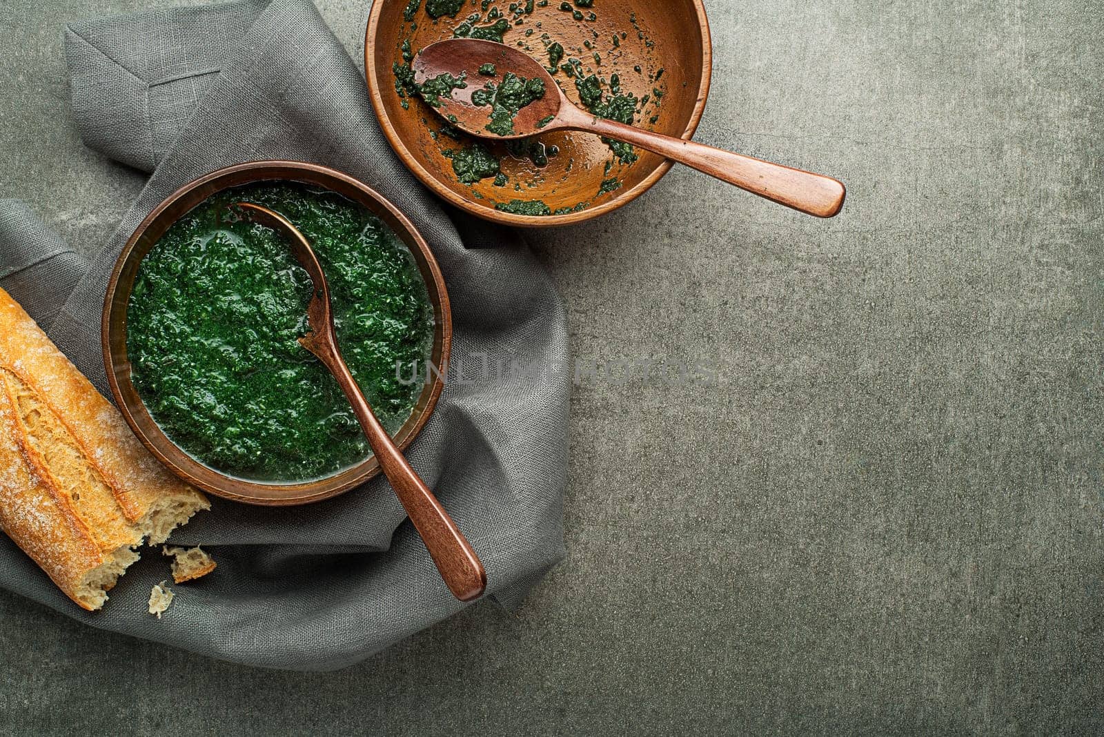 Eating spring healthy meal. Green creamy soup with vegetables and herbs and bread