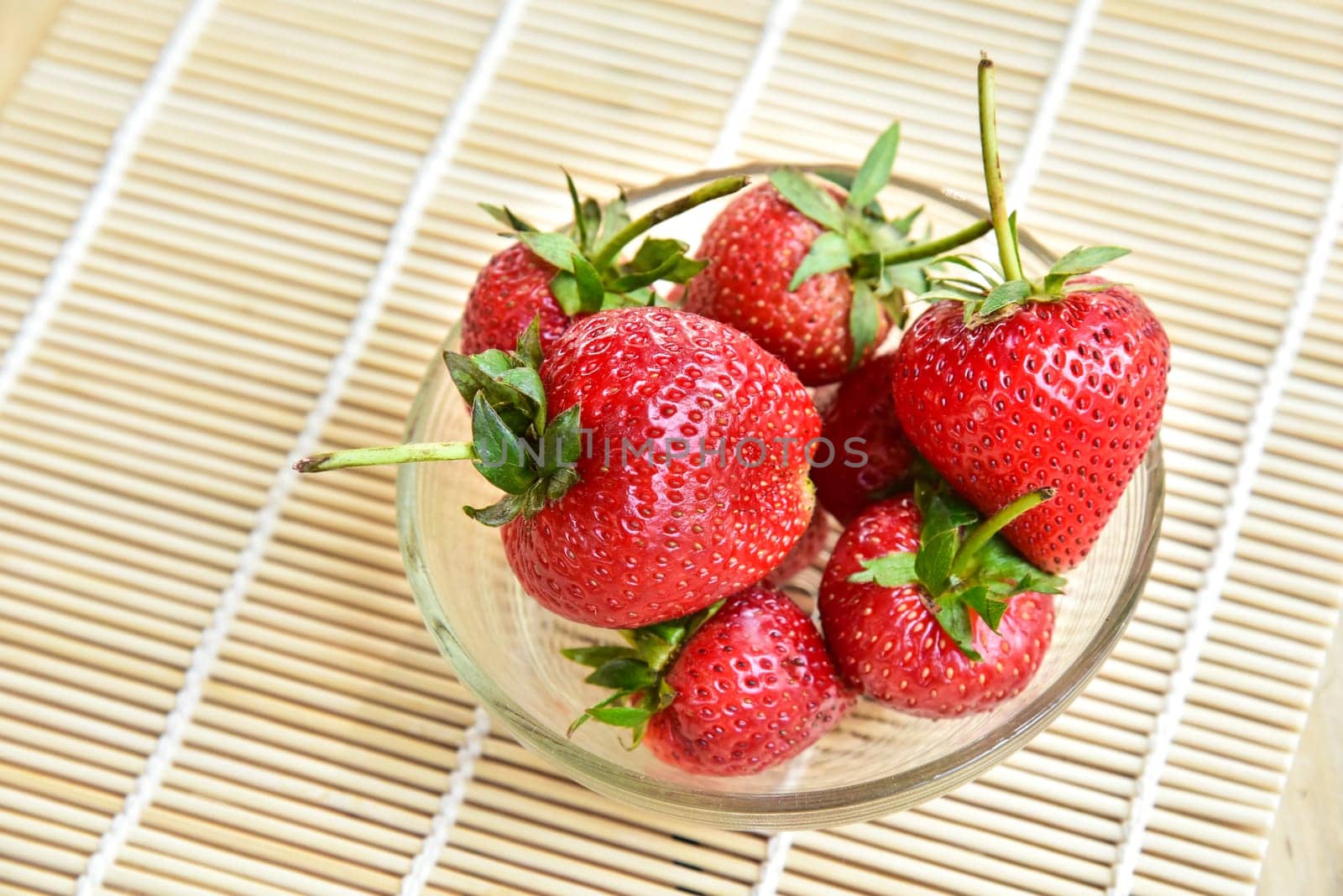 Fresh strawberries in a bowl on bamboo background