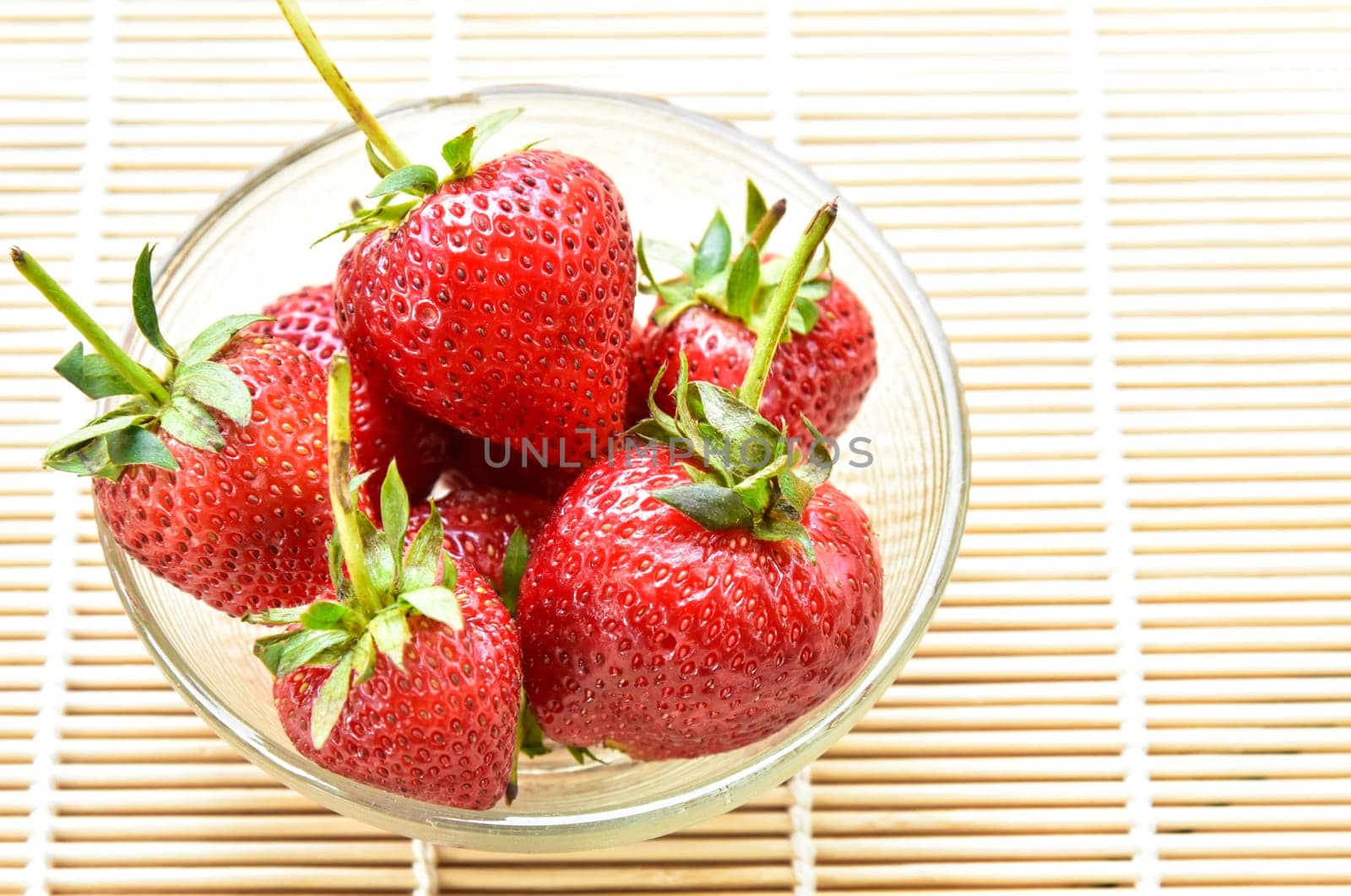 Fresh strawberries in a bowl on bamboo background