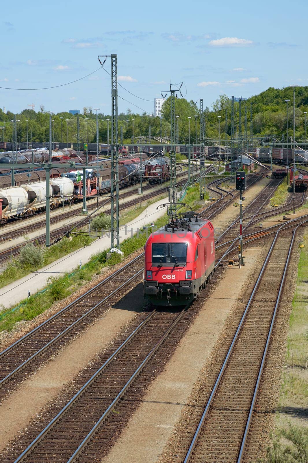 Munich, Germany - July 10, 2019: Red locomotive of Oebb transportation company moving through railroad cargo marshalling station.