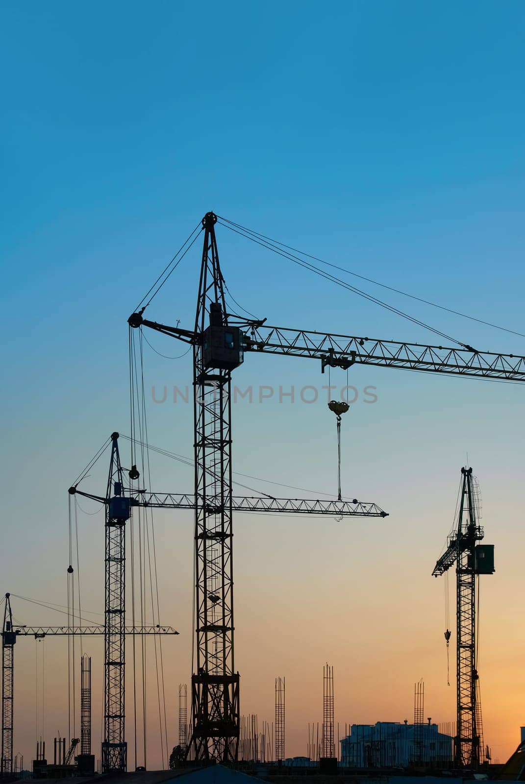 Industrial landscape with silhouettes of cranes on the sunset background