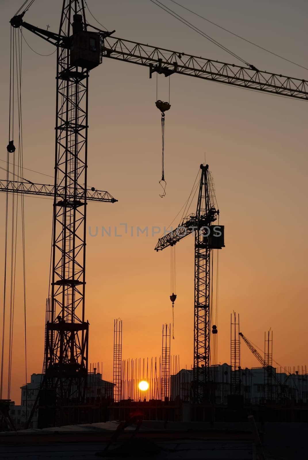Industrial landscape with silhouettes of cranes on the sunset background