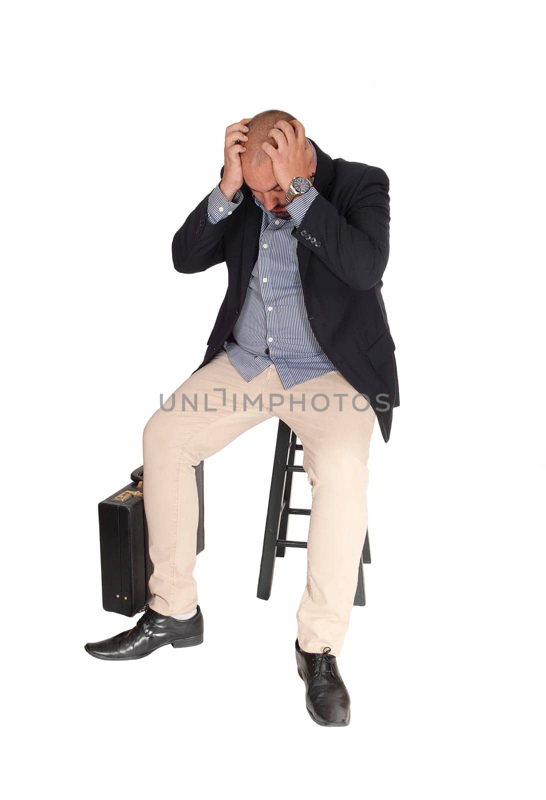 A middle age business man sitting with his hands on his head thinking.about his problem, isolated for white background.