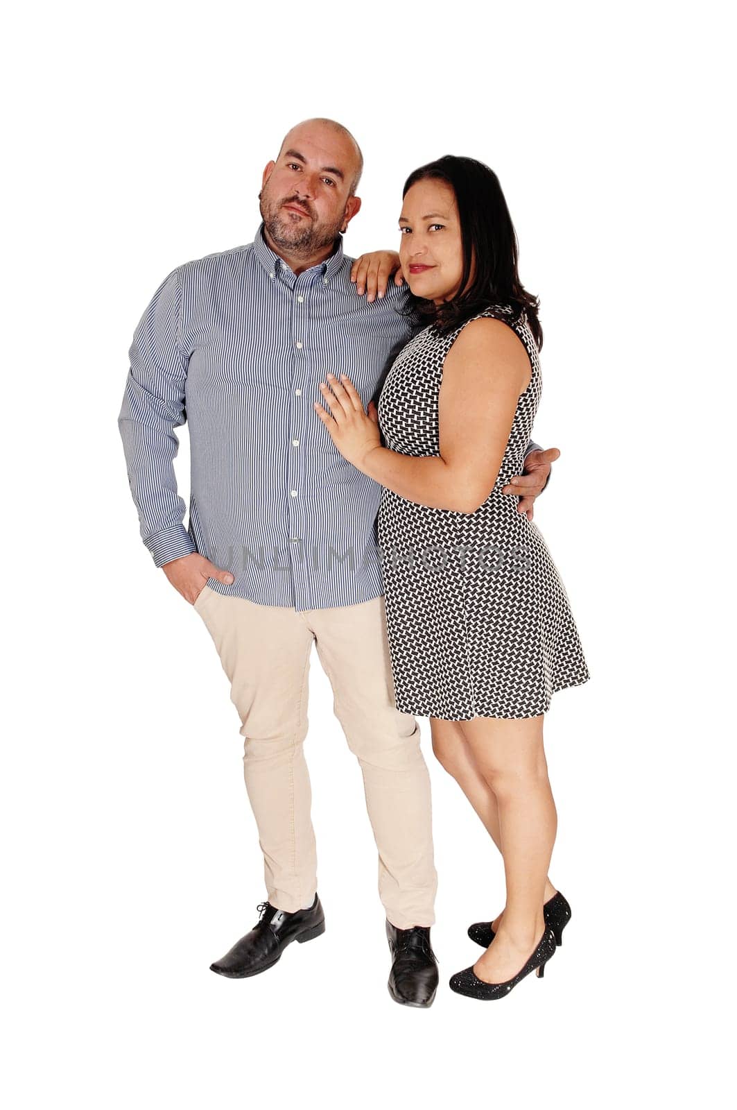 A middle age Hispanic couple standing in the studio arm in arm and.smiling into the camera, isolated for white background.