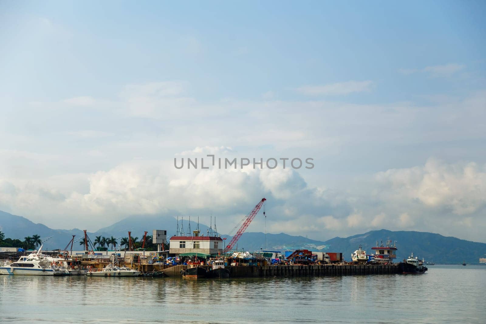 View of the fishing harbor in the bay against the backdrop of mountains and clouds on a clear morning, Shenzhen, China