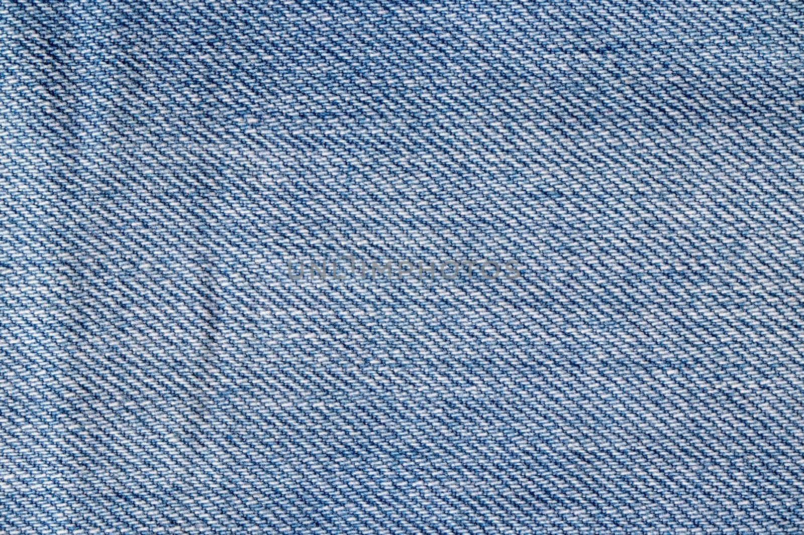 Denim background texture. Close-up of details of empty light blue jeans fabric jean surface. Macro. Top view. Beautiful backdrop.
