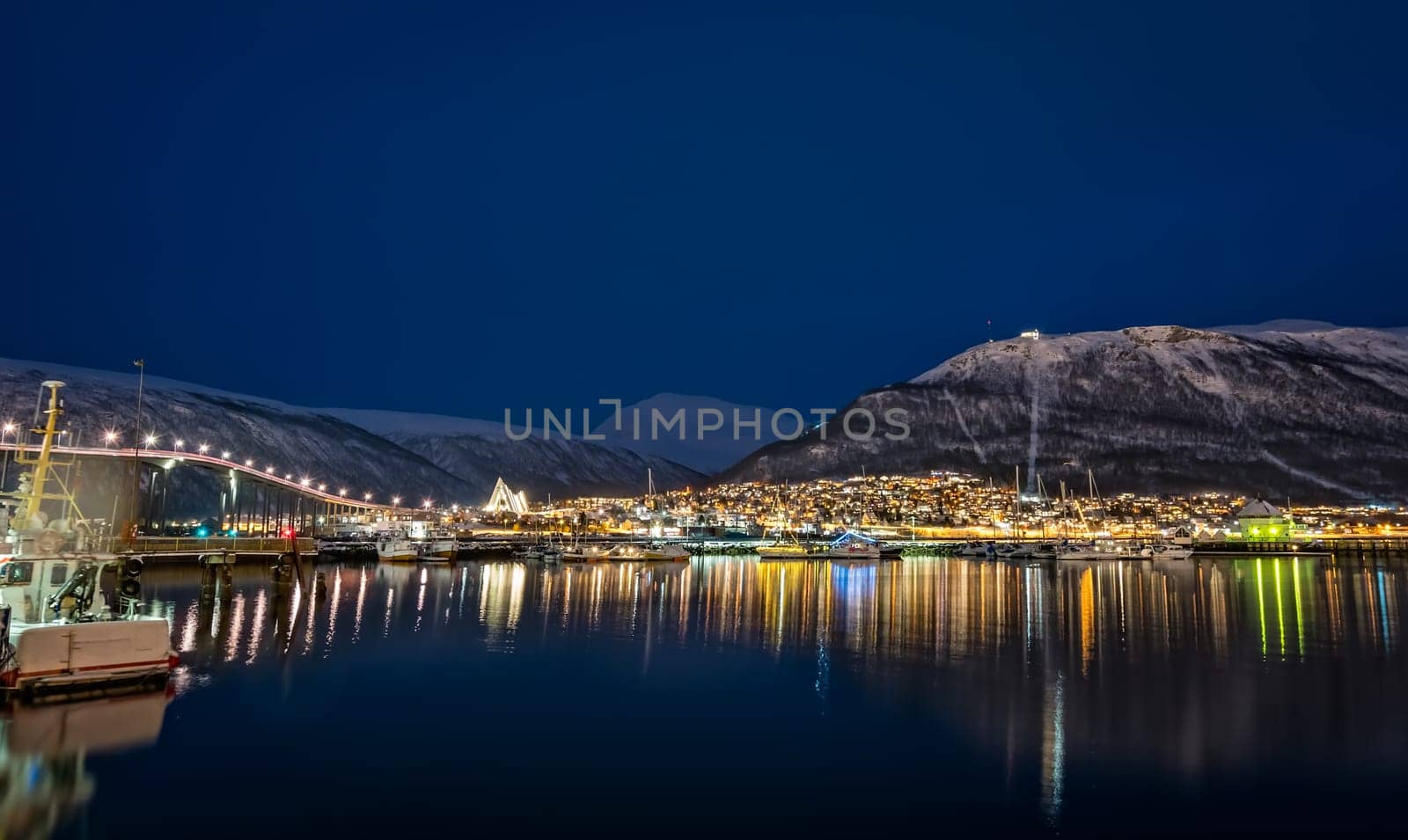Panorama of port and harbour with famous Tromso Bridge across Tromsoysundet strait in the background, photographed at night, Northern Norway