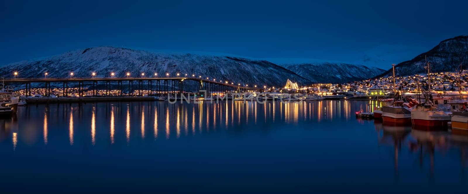 Panorama of port and harbour with famous Tromso Bridge across Tromsoysundet strait in the background, photographed at night, Northern Norway
